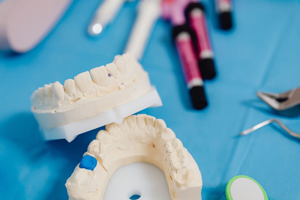 Plomby dentystyczne na modelu uzębienia obok narzędzi stomatologicznych